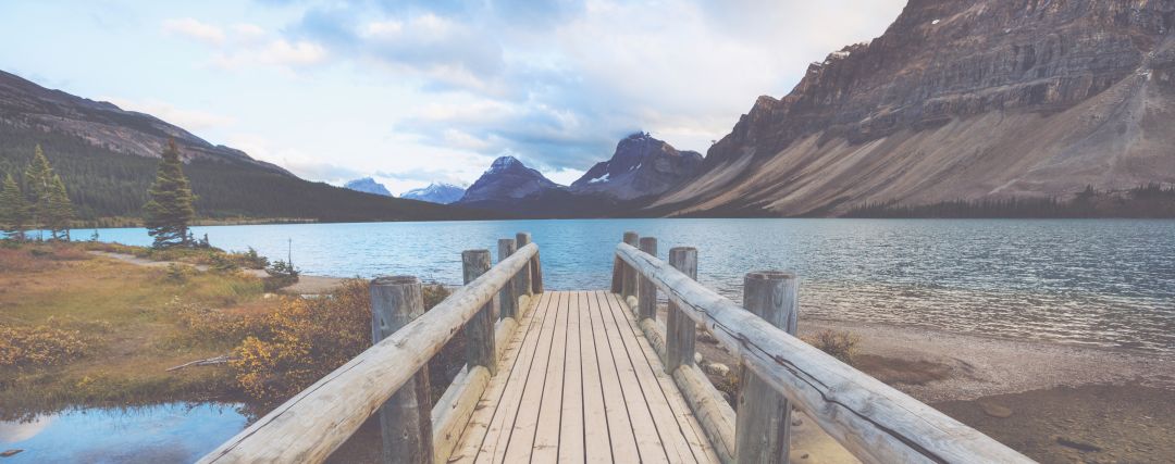 Board walk leading to a lake surrounded by mountains