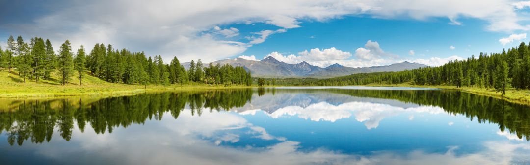 A calm lake surrounded by countryside with the sky reflecting in the water