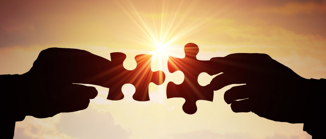 Connecting puzzle pieces held up to the sun